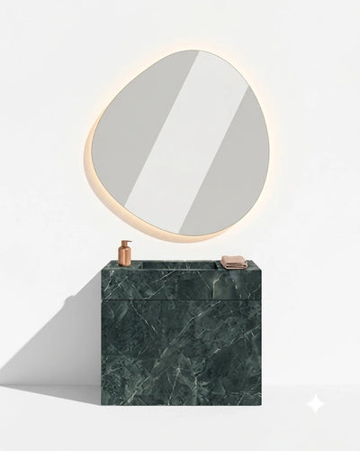 A modern bathroom vanity setup with a dark green marble sink block, a copper faucet, and a matching oval backlit mirror mounted on a white wall.