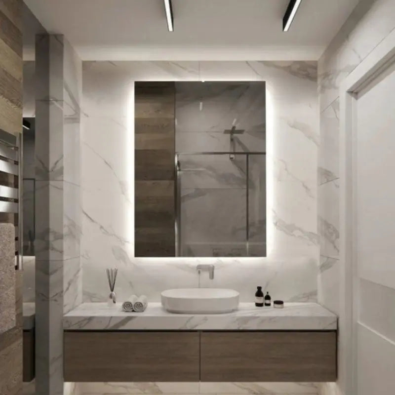 Rectangular LED mirror with rear lighting above a vanity in a marble bathroom