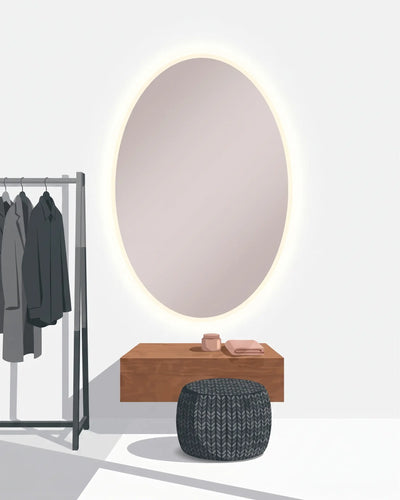 An oval backlit vanity mirror mounted on a white wall above a wooden console table, with a dark woven pouf in front and a clothing rack with gray garments to the left.
