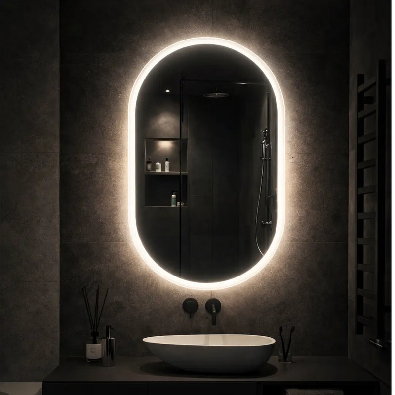 Bathroom with a large oval mirror illuminated by LED lights on a dark wall.