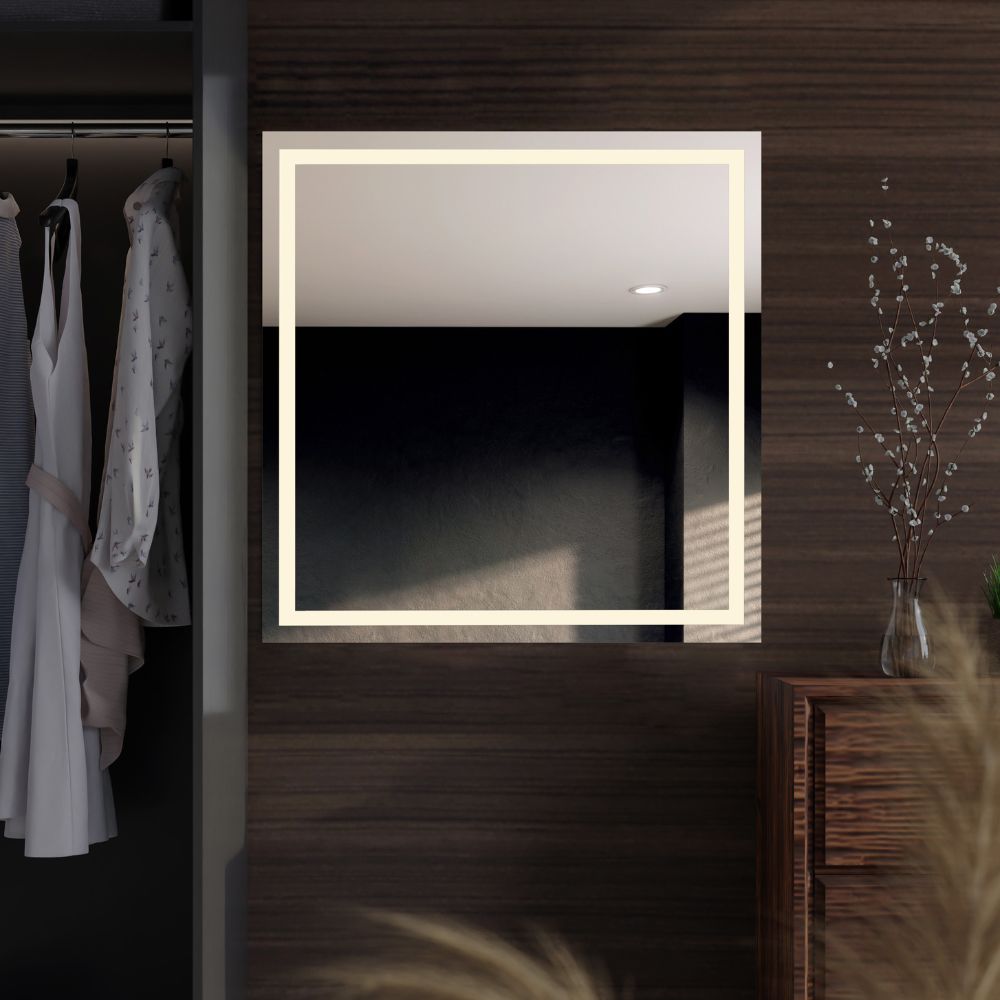 A square LED mirror with double front lighting, mounted on a wooden wall, with a dim reflection of clothes and a vase visible in the mirror.