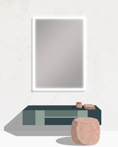 A modern minimalist interior scene featuring a large rectangular wall mirror with a glowing white LED frame, mounted above a dark floating console table. In front of the table is a round blush pink stool, with small decorative objects on the tabletop.